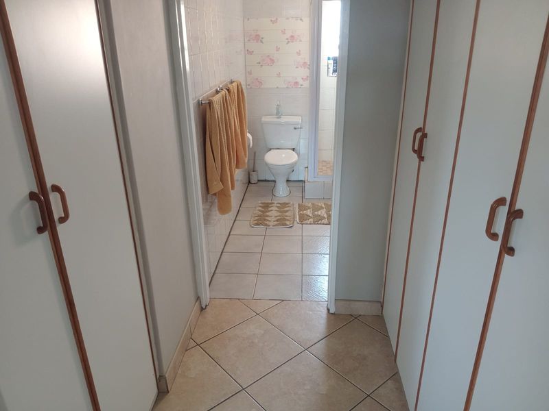 A functional bathroom featuring built-in storage cupboards, tiled flooring, and a separate shower enclosure, offering potential for modern cosmetic updates.