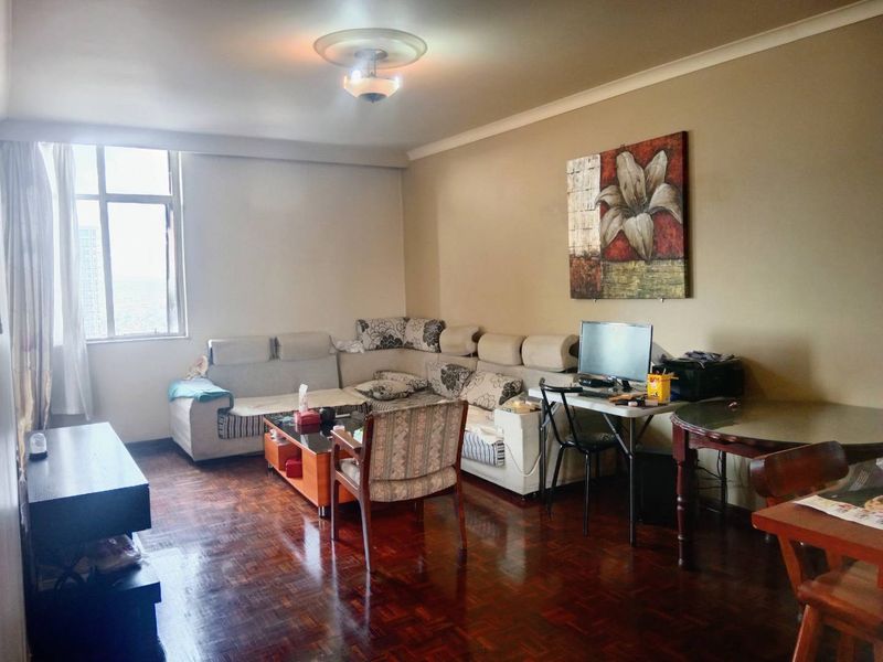 A spacious living room featuring classic parquet flooring, decorative ceiling rose, and coving, offering a comfortable and functional living space.
