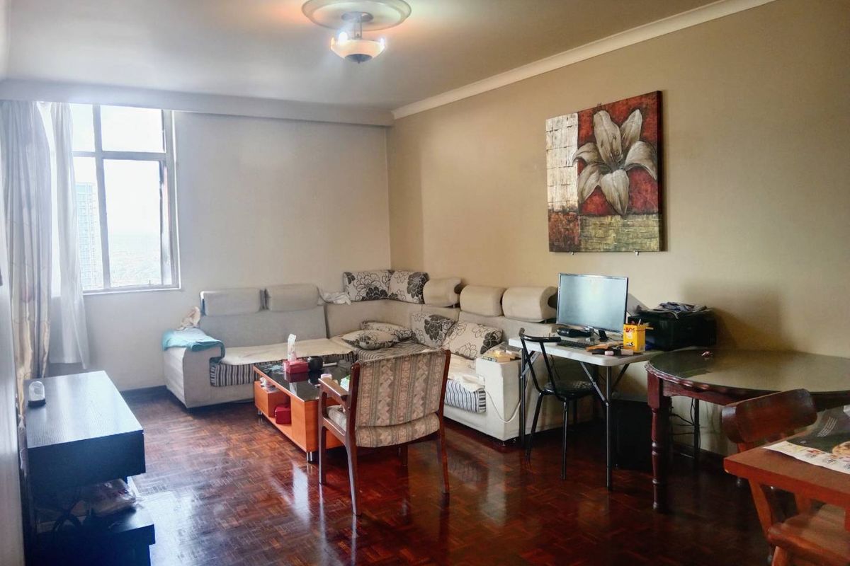 A spacious living room featuring classic parquet flooring, decorative ceiling rose, and coving, offering a comfortable and functional living space.