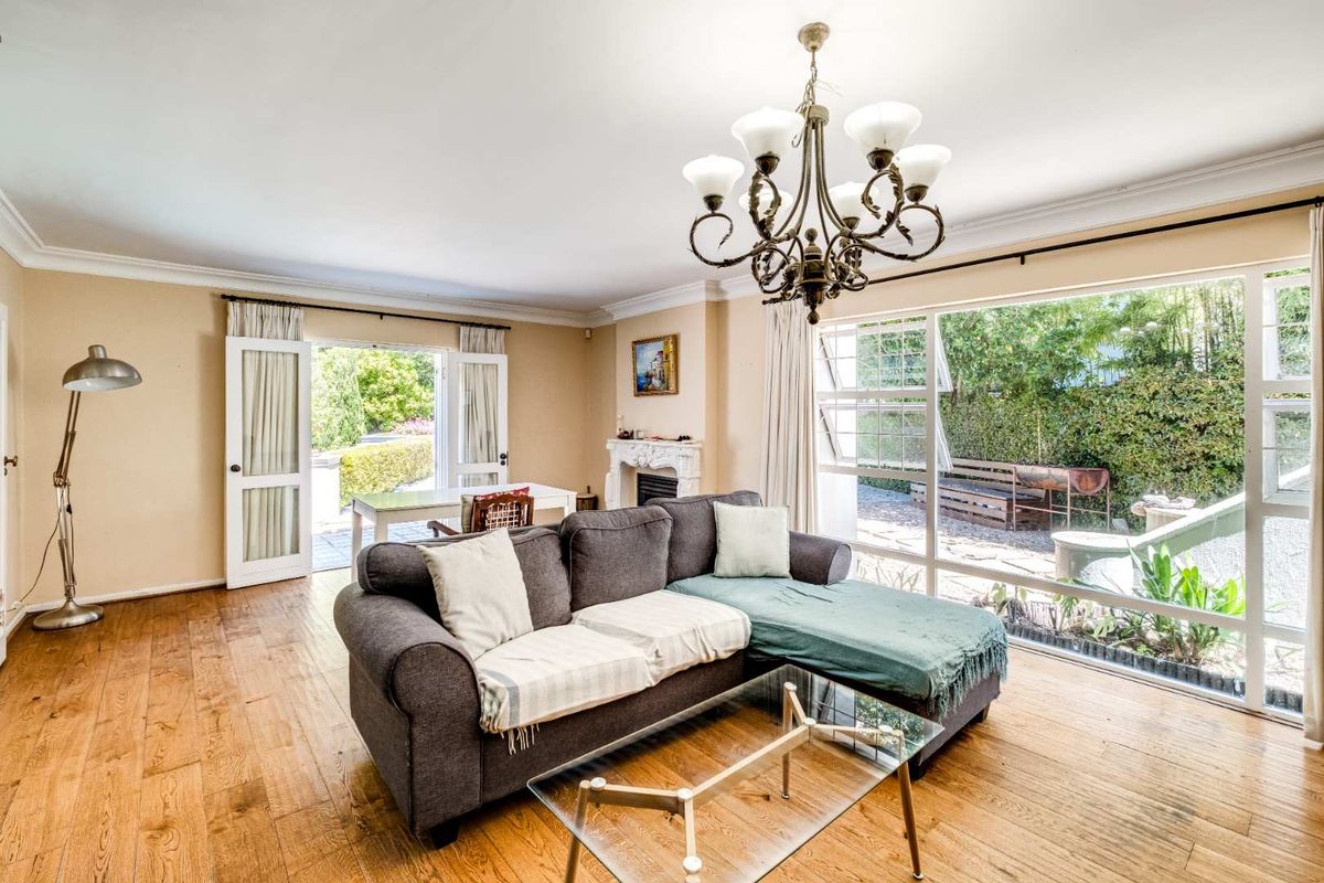 Spacious living room featuring timber flooring, a decorative fireplace, and large windows providing direct access to the outdoor patio area.
