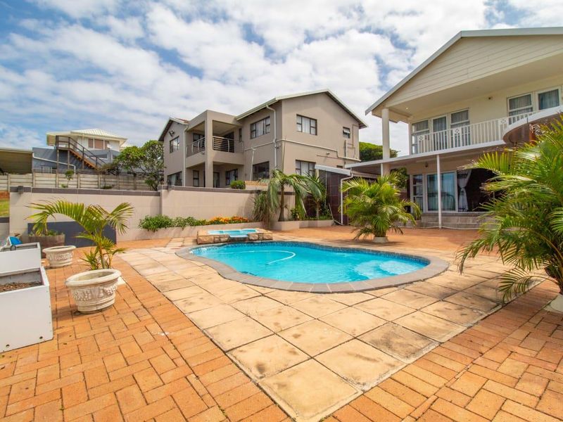 Outdoor pool area featuring a paved patio, integrated pool, and boundary wall, adjacent to the main townhouse structure with a covered veranda and balcony.