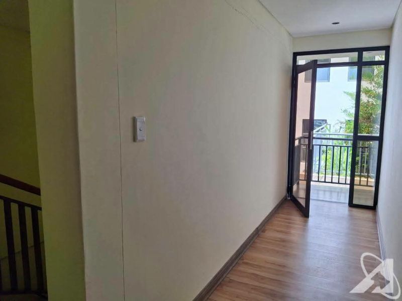 A bright, empty hallway featuring laminate flooring and a glass door leading to an outdoor balcony area.