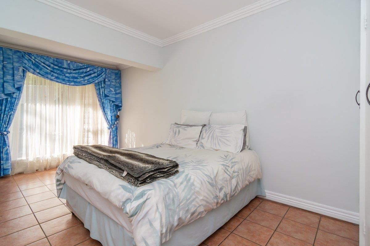 A bedroom featuring tiled flooring, crown molding, and a large window with natural light.