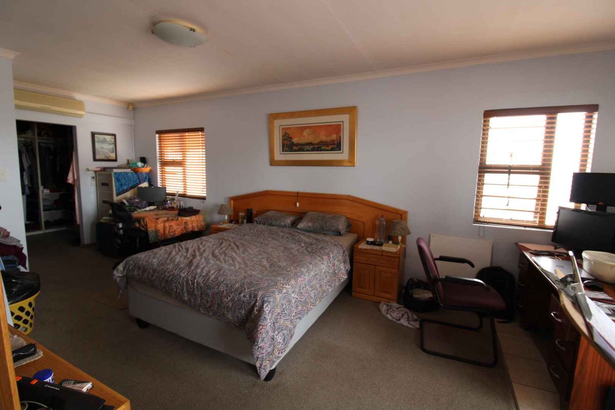A spacious bedroom featuring carpeted flooring, built-in closet space, and dual windows with fitted blinds, providing natural light and functional storage.
