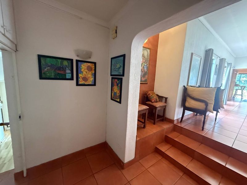 An inviting entryway featuring terracotta floor tiles and a distinctive arched doorway leading to a raised living area.