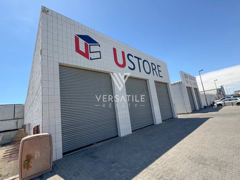 Front elevation of an industrial storage facility featuring tiled facade, multiple roller shutter doors, and paved exterior access area.