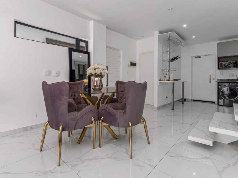 Modern open-plan living area featuring polished marble-look floor tiles, recessed lighting, a floating staircase, and integrated kitchen and laundry cabinetry.