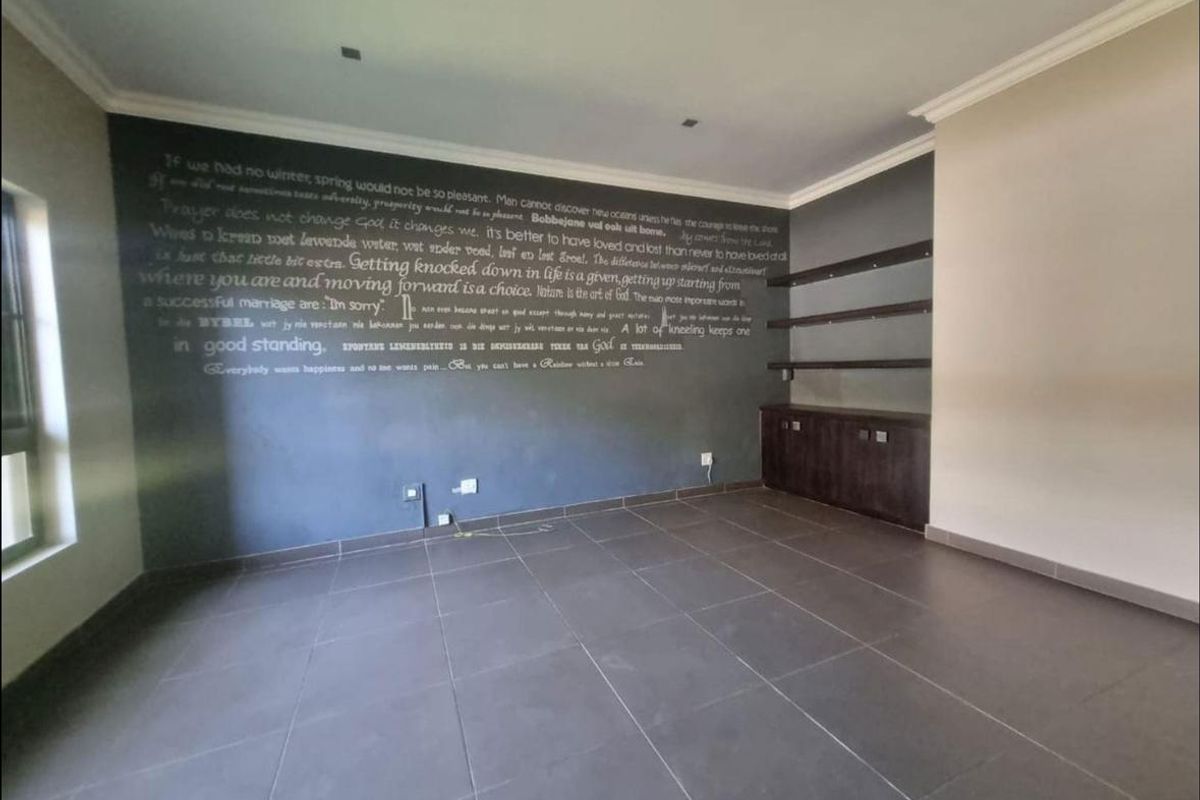 Spacious living area featuring large format floor tiles, a dark feature wall with built-in shelving, and recessed ceiling lighting.