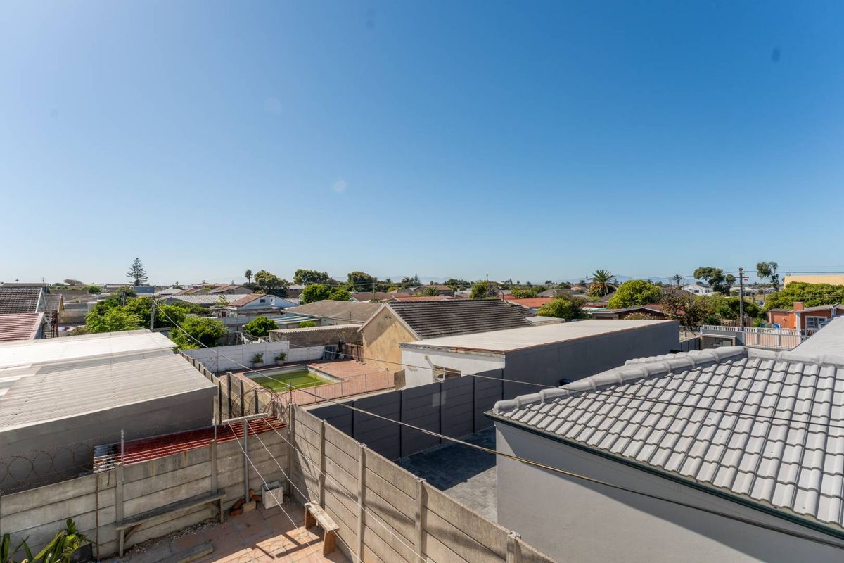 Elevated aerial view overlooking the surrounding residential neighborhood, showcasing neighboring rooftops, boundary walls, and a small swimming pool.