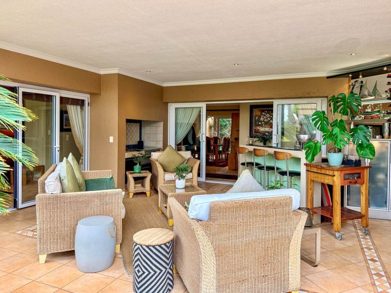 Spacious covered patio featuring a built-in braai, integrated bar counter, and tiled flooring, providing a seamless transition to the interior living spaces.