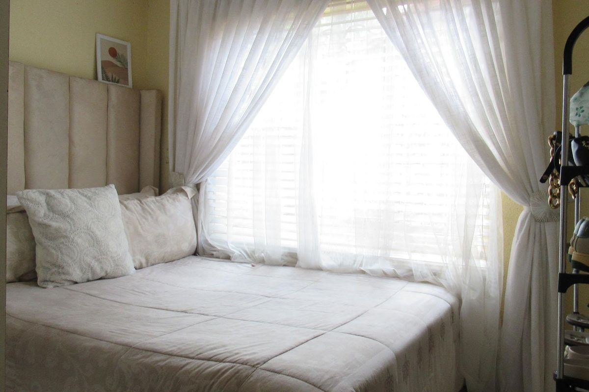 A cozy bedroom featuring a built-in headboard and large window with natural light, creating a bright and inviting sleeping space.