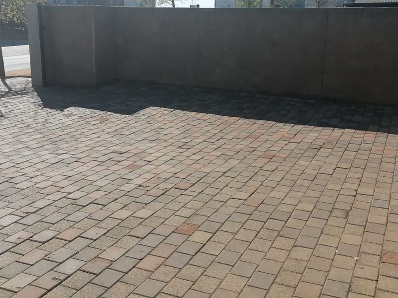 A paved front driveway area enclosed by a boundary wall and metal gate, providing secure off-street parking space.