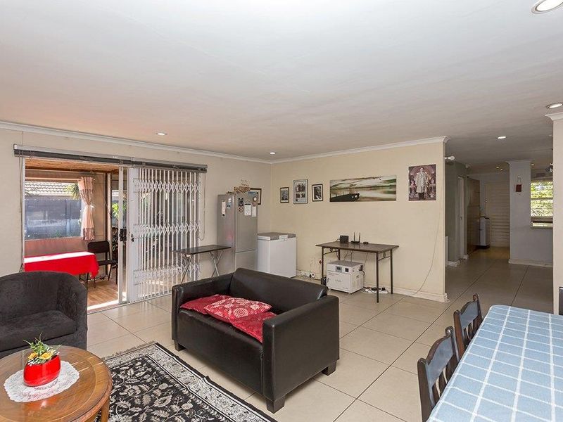 Spacious open-plan living and dining area featuring tiled flooring, recessed lighting, and a sliding door providing access to the outdoor patio.