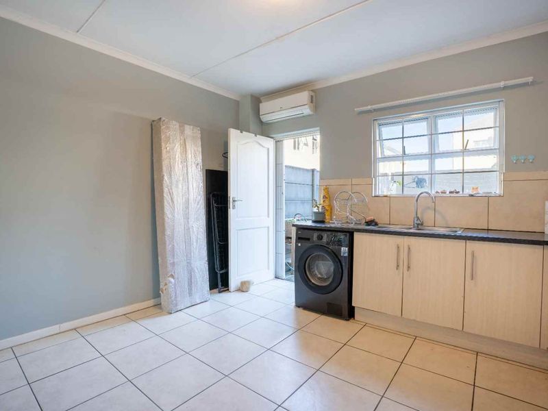 Functional kitchen area featuring built-in cabinetry, laminate countertops, a stainless steel sink, and tiled flooring with direct access to an exterior door.
