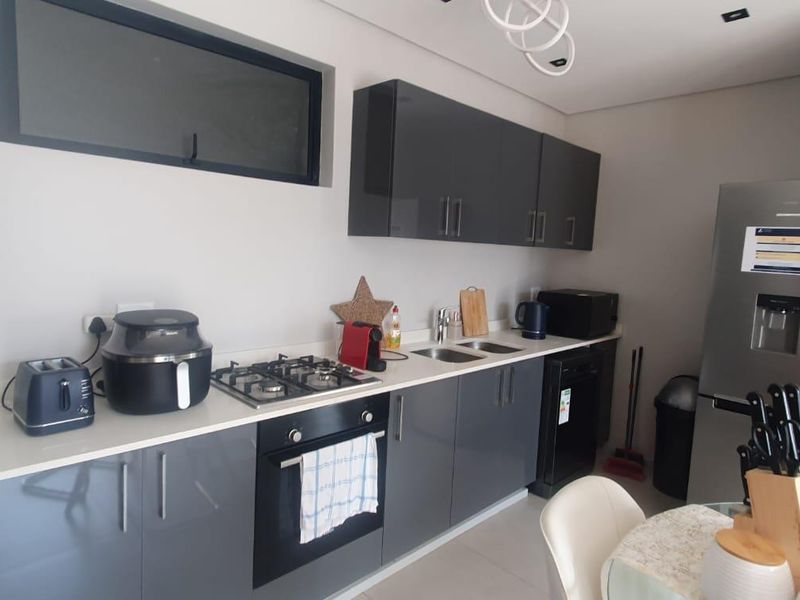 Modern kitchen featuring sleek grey cabinetry, stone countertops, a gas hob, and built-in oven, offering a clean and functional culinary space.