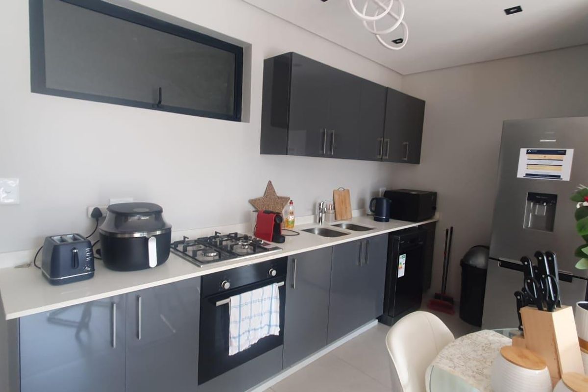 Modern kitchen featuring sleek grey cabinetry, stone countertops, a gas hob, and built-in oven, offering a clean and functional culinary space.