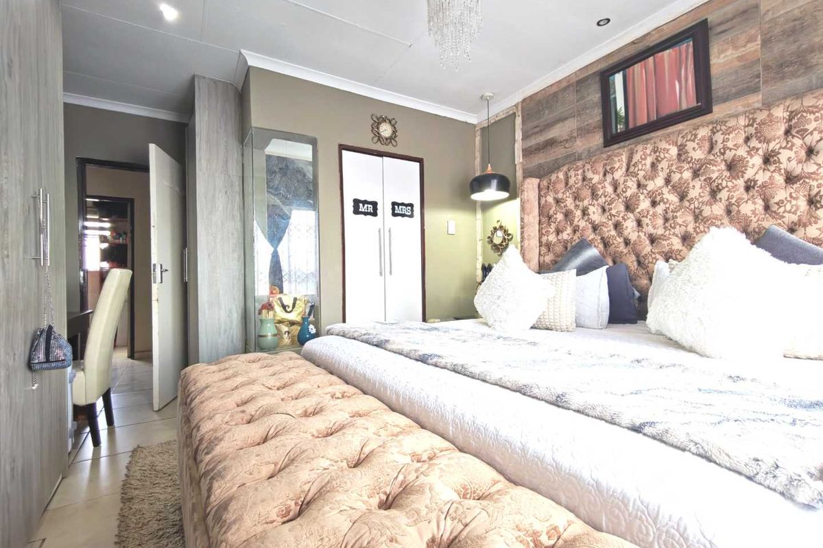 A well-maintained bedroom featuring built-in cupboards, tiled flooring, and decorative wall paneling with integrated lighting.