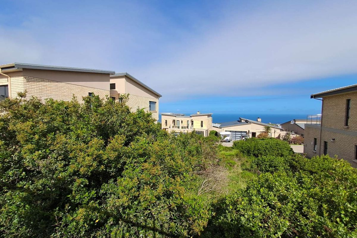 A scenic view overlooking a residential neighborhood with coastal landscape and ocean horizon in the distance.