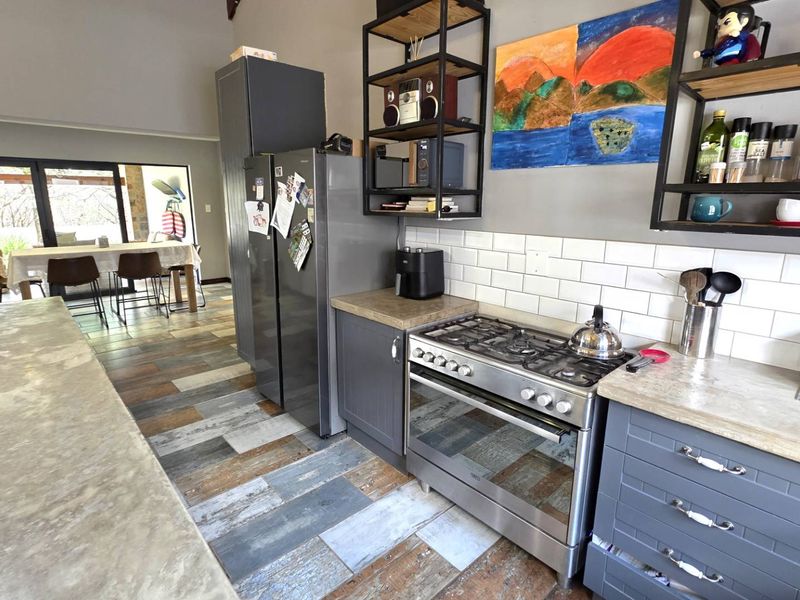 Modern kitchen featuring grey shaker cabinetry, subway tile backsplash, gas cooktop, and integrated oven, with a seamless transition to the adjacent dining area.