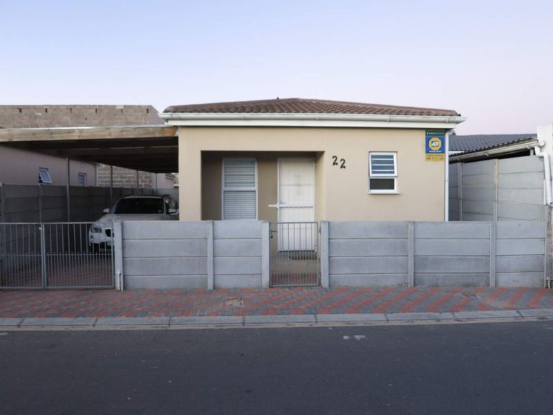 Front elevation of a single-story house featuring a concrete perimeter wall, metal gate, and an attached carport.