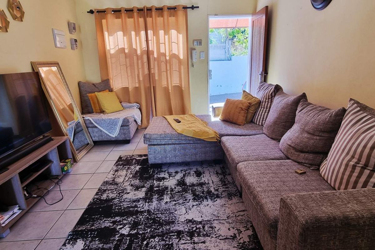 A comfortable living room featuring tiled flooring and direct access to an outdoor patio area through a glass sliding door.