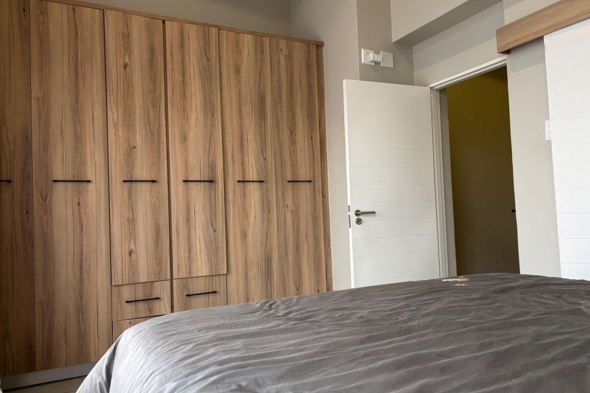 A well-maintained bedroom featuring modern built-in wooden cabinetry with sleek black handles and a neutral interior finish.
