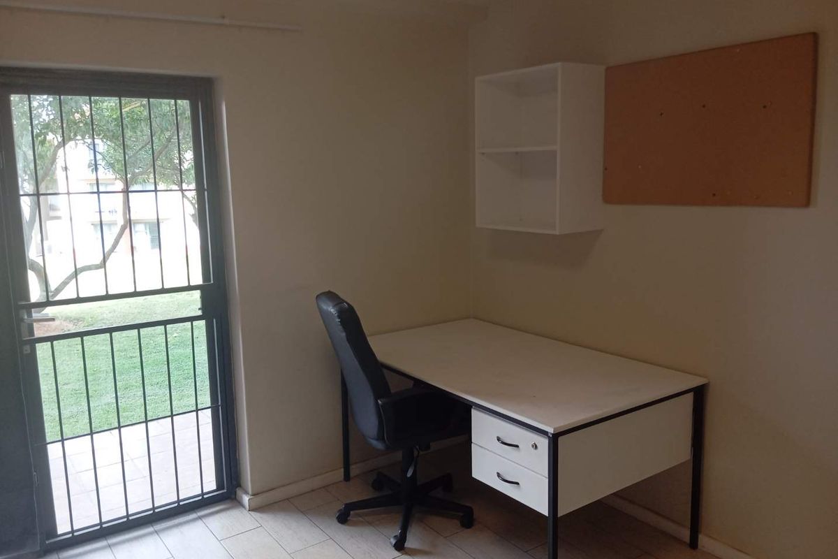 A functional home office space featuring tiled flooring and a secure exterior door with direct access to the garden area.