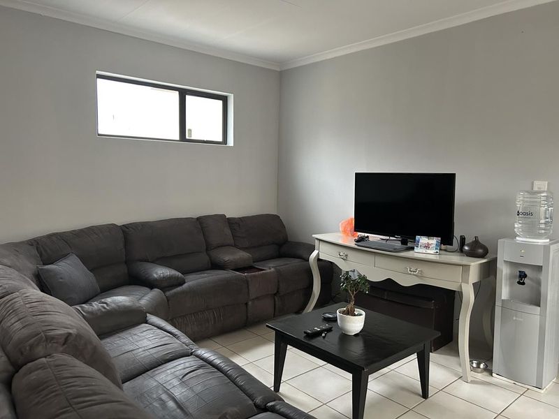 A comfortable living room featuring neutral wall tones, tiled flooring, and a horizontal window providing natural light.