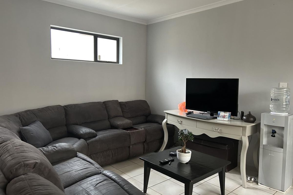 A comfortable living room featuring neutral wall tones, tiled flooring, and a horizontal window providing natural light.