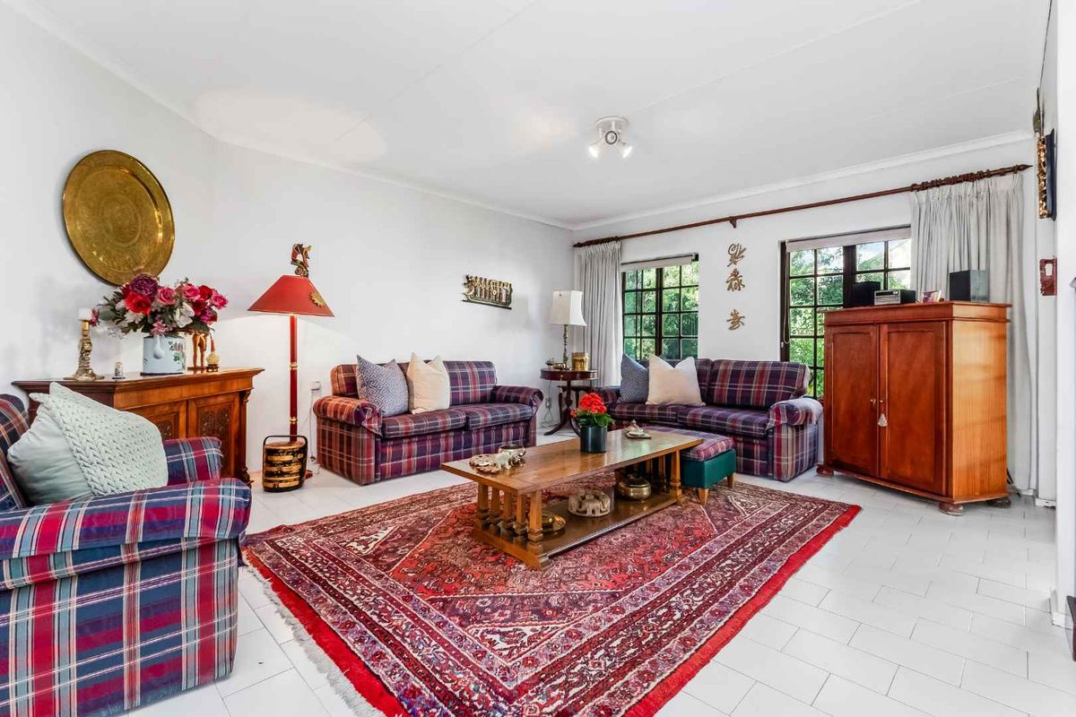 A spacious living room featuring tiled flooring, large windows with curtain rods, and ceiling-mounted lighting fixtures.