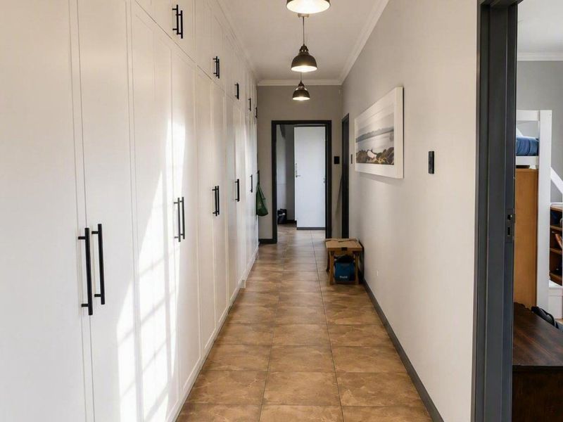 A bright, well-maintained hallway featuring extensive built-in storage cabinetry and tiled flooring, leading towards additional rooms.