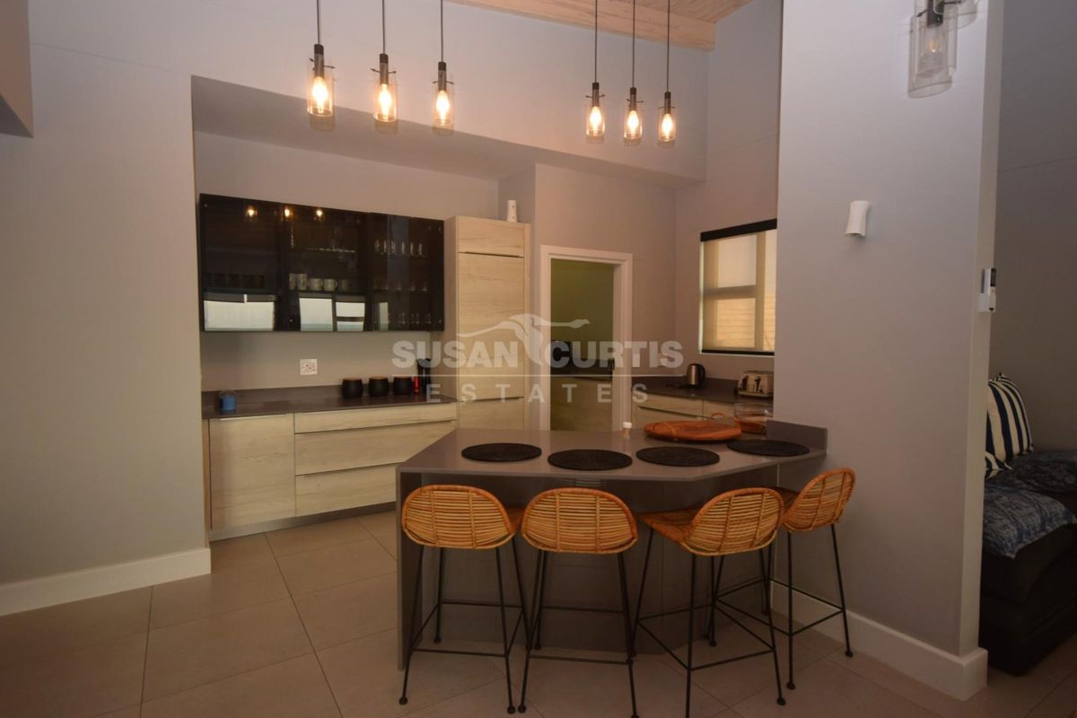 Modern kitchen featuring sleek built-in cabinetry, stone countertops, a functional breakfast bar, and contemporary pendant lighting in an open-plan layout.