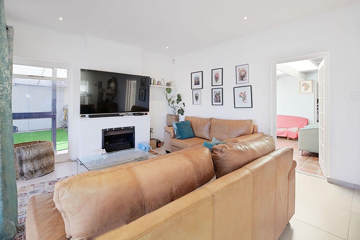 A bright living room featuring a built-in fireplace, tiled flooring, and direct access to an outdoor patio area.