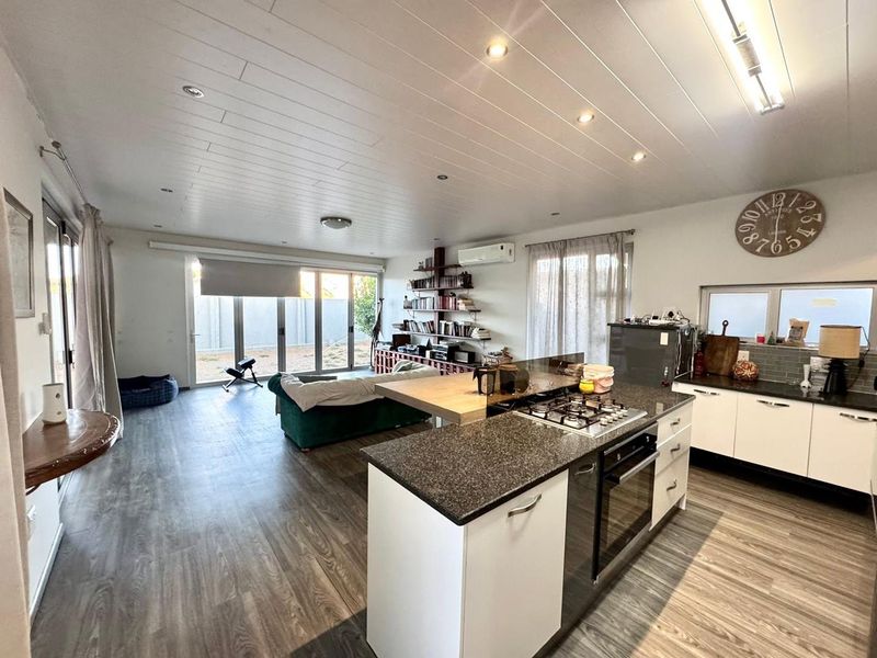 Spacious open-plan living area featuring a modern kitchen with a central island, gas hob, built-in oven, and seamless flow to the outdoor patio area.
