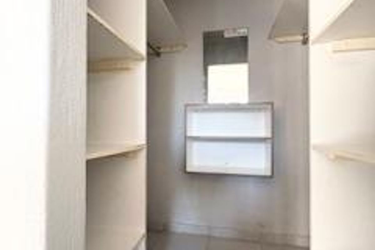 A walk-in closet area featuring built-in shelving units, hanging rails, and tiled flooring.