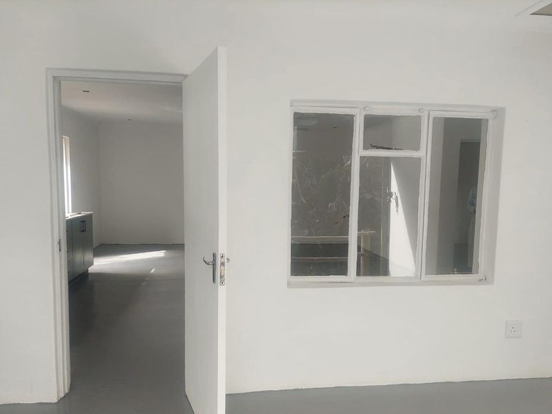 A bright, empty hallway featuring a white interior door and a multi-pane window, providing a clean, neutral space ready for personalization.