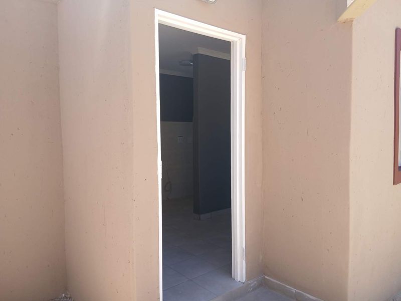 An exterior view looking into a small utility or storage space with tiled flooring and painted walls.