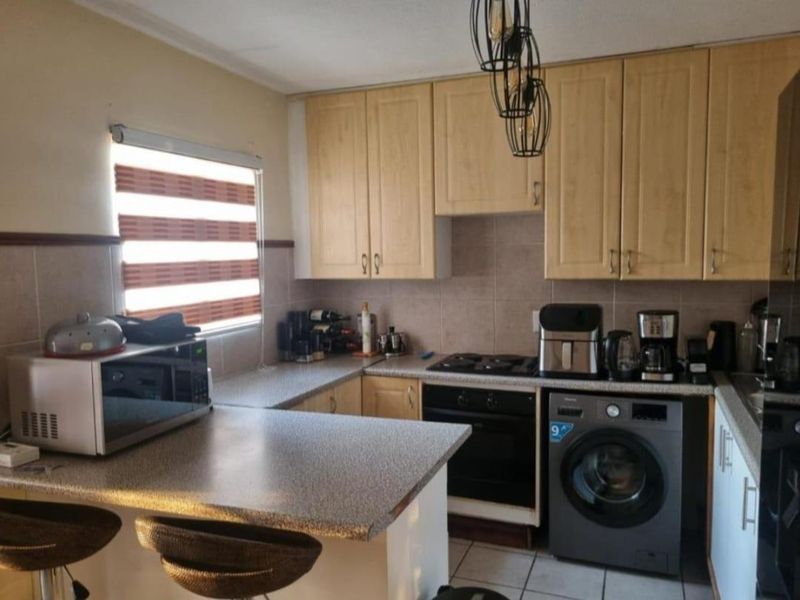 A functional kitchen featuring light wood-finish cabinetry, laminate countertops, a breakfast nook, and integrated cooking appliances with tiled flooring and backsplash.