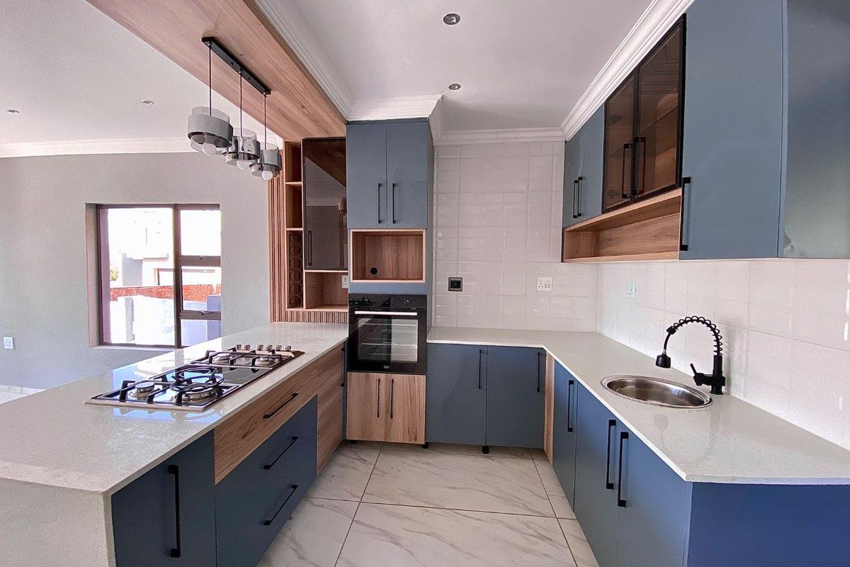 Modern kitchen featuring two-tone cabinetry, stone countertops, a built-in oven, gas hob, and a sleek undermount sink with a contemporary faucet.