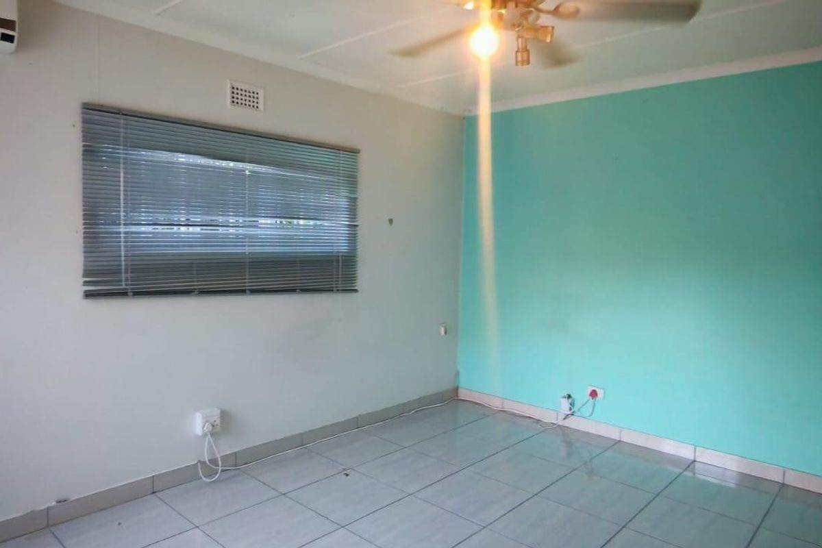 An empty bedroom featuring tiled flooring, a ceiling fan, an air conditioning unit, and a window with venetian blinds.