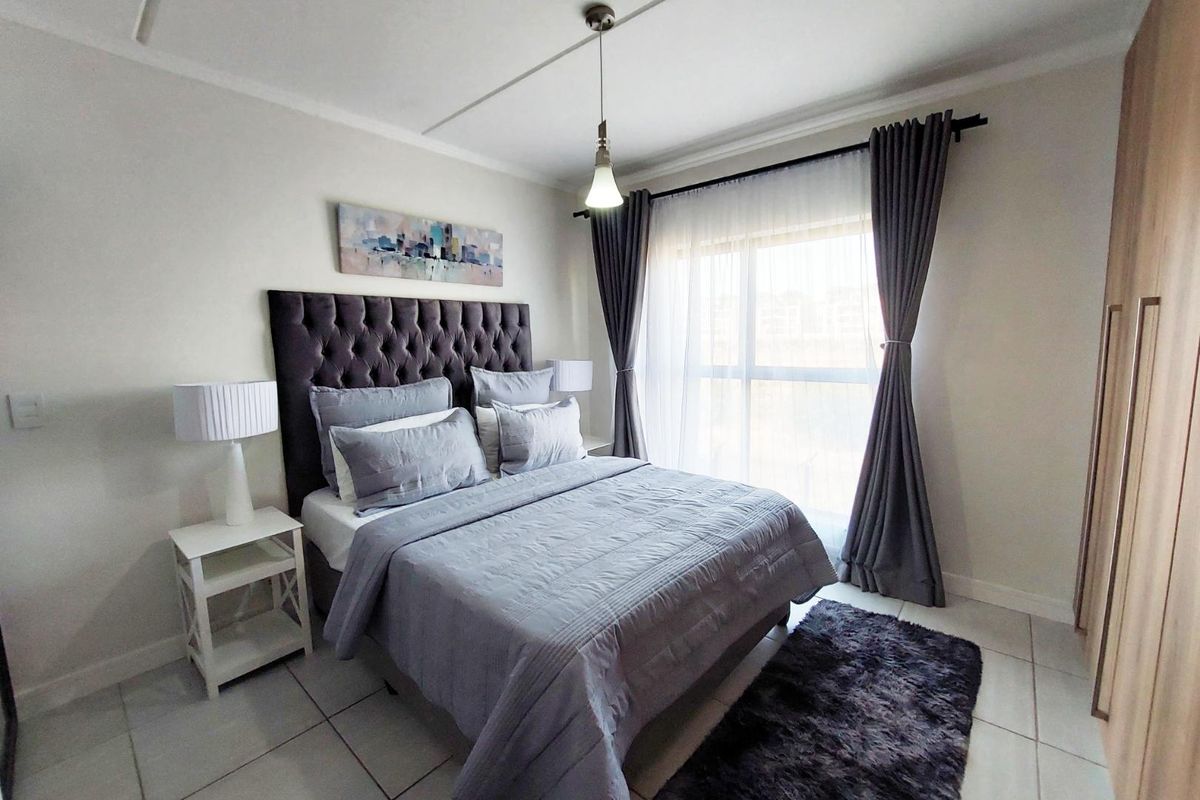A well-maintained bedroom featuring tiled flooring, a built-in wardrobe, and a large window with curtain fittings, providing a bright and comfortable living space.