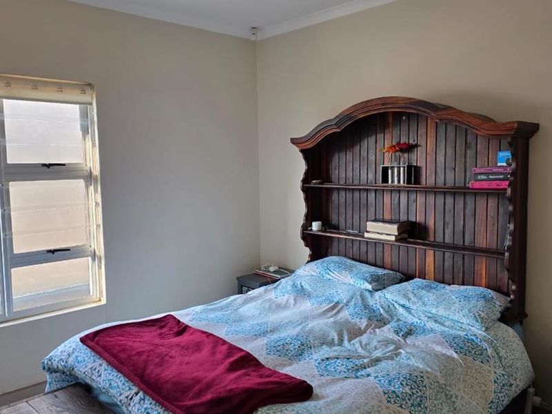 A bedroom featuring tiled flooring, neutral wall paint, and an aluminium window frame, providing a functional and well-lit sleeping space.