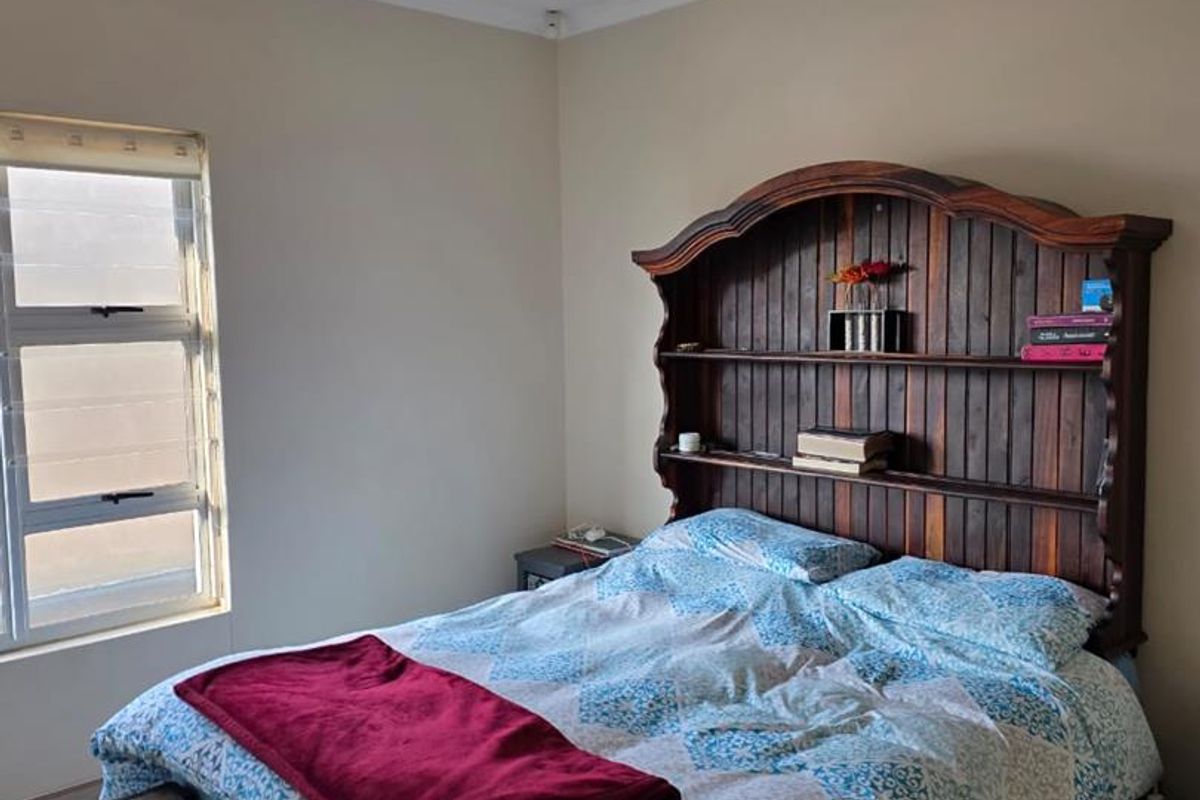A bedroom featuring tiled flooring, neutral wall paint, and an aluminium window frame, providing a functional and well-lit sleeping space.
