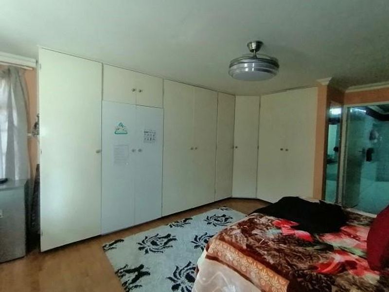 A bedroom featuring extensive floor-to-ceiling built-in cupboards and a central ceiling fan.