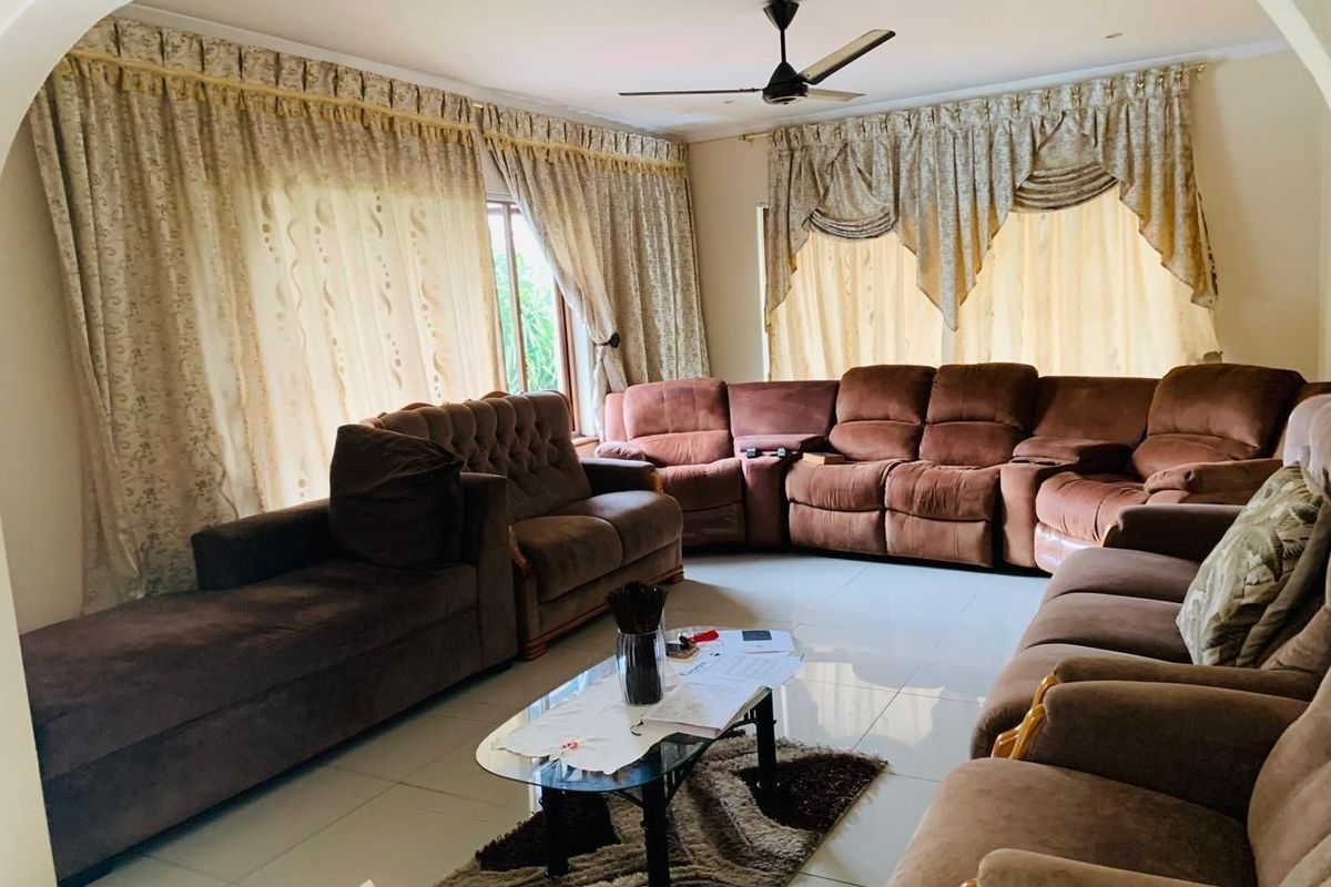 Spacious living room featuring tiled flooring, a ceiling fan, and an arched entryway, providing a comfortable and functional family space.
