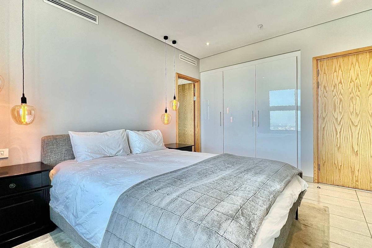 Modern bedroom featuring built-in high-gloss cabinetry, recessed ceiling air conditioning, and contemporary pendant lighting with tiled flooring.