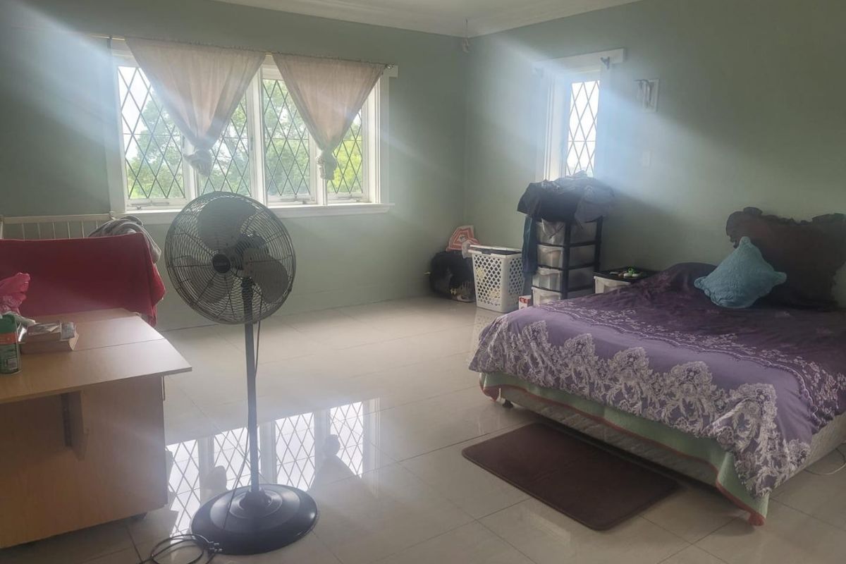 Spacious bedroom featuring large leaded glass windows, neutral wall tones, and polished tiled flooring, offering a bright and airy atmosphere.