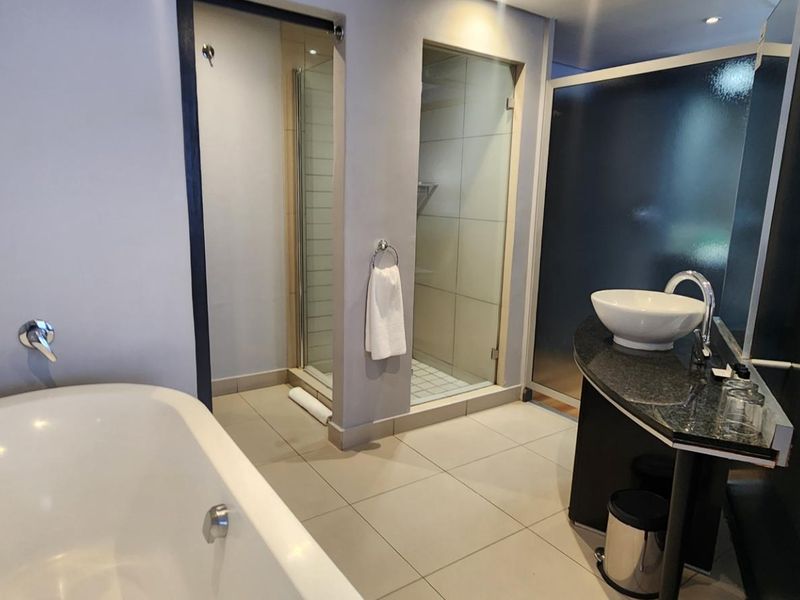 Modern bathroom featuring a freestanding bathtub, a separate glass-enclosed shower, and a sleek vessel sink set on a granite vanity countertop.