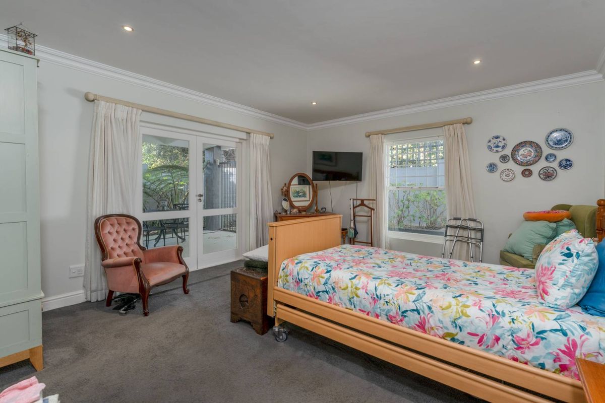 Spacious bedroom featuring neutral walls, crown molding, recessed lighting, carpeted floors, and direct access to a private patio through double glass doors.