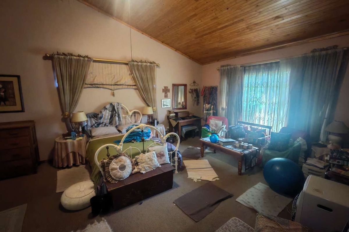 Spacious bedroom featuring a high vaulted timber ceiling, carpeted flooring, and large windows with security bars.